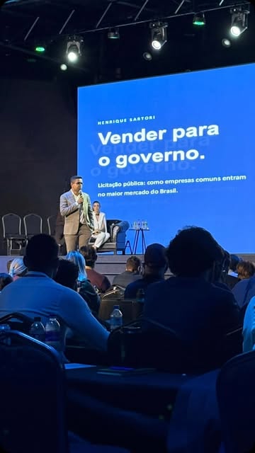 Henrique Sartori no palco durante apresentação sobre licitações públicas
